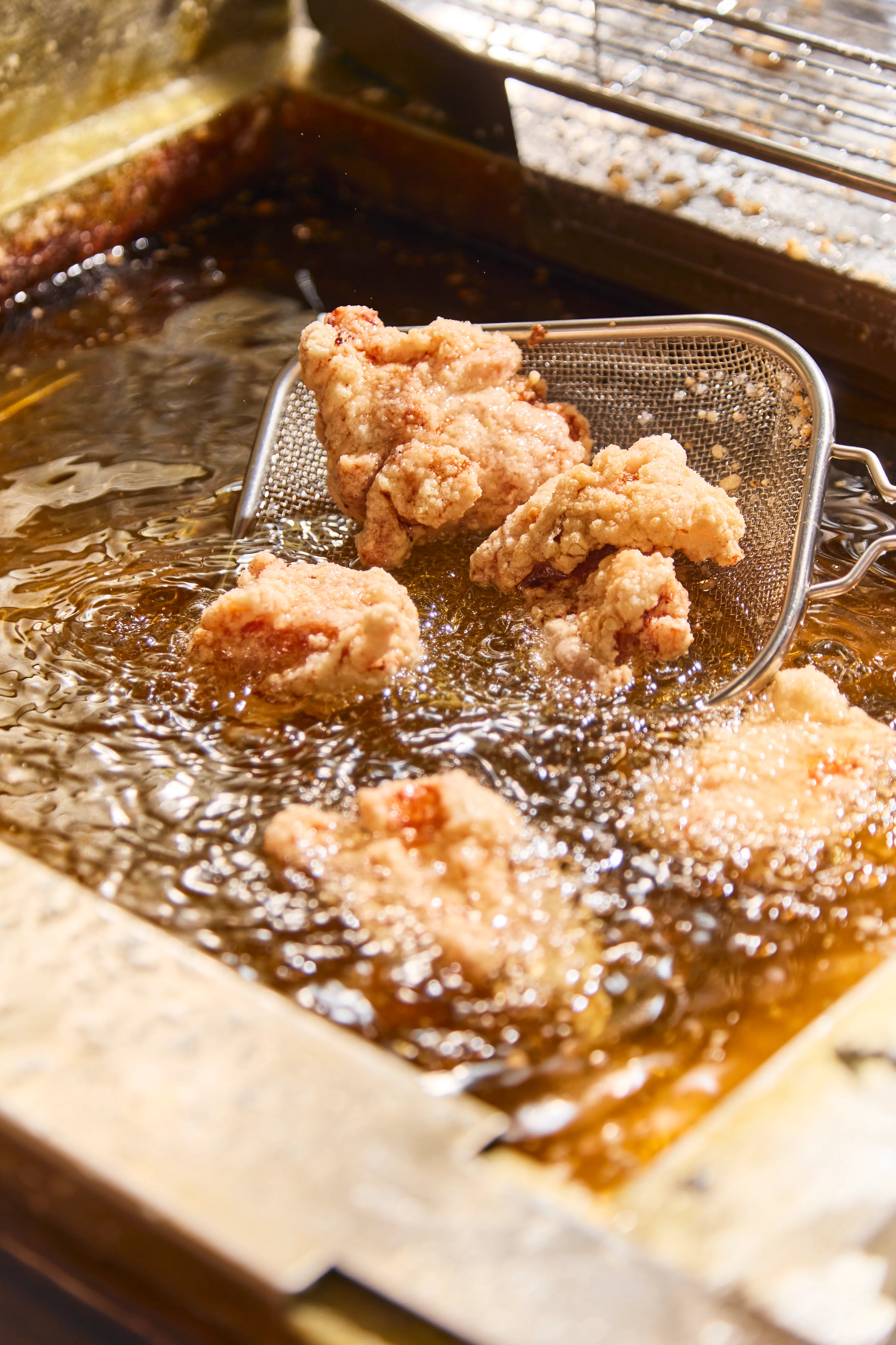 揚げたてのサクサクからあげを油からすくい上げる様子 - からあげ日和